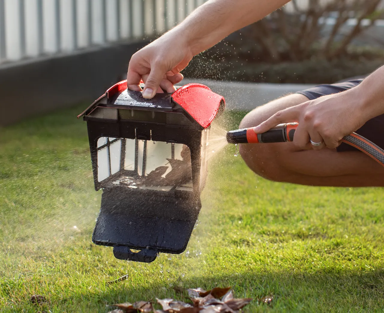 L'utilisateur rince sans effort les feuilles du grand panier à débris de l'iGarden Pool Cleaner K Pro avec un tuyau d'arrosage